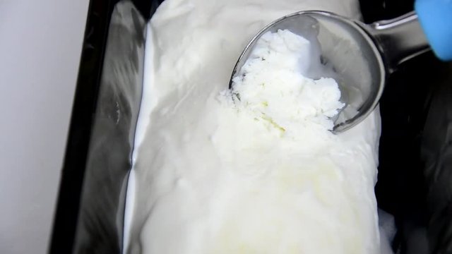 Vanilla ice cream Flat lay. Top view. Spoon for ice cream takes a little out of the package. Macking ball of ice cream.