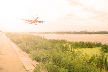 Airliner over the river. Sunset in the sky.
