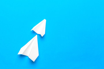 Flat lay of white paper plane and blank paper on pastel blue color background