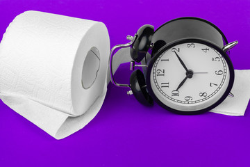 Alarm clock with toilet paper on a purple background