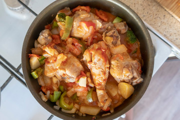 Chicken stew with vegetables in a frying pan, close-up, top view.