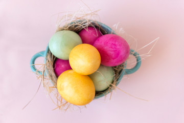 pink , yellow, green Easter eggs in a plate, top view
