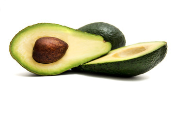 green avocado cut in half lying on a white background