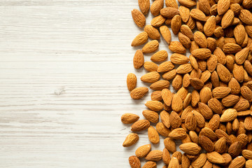 Almonds on a white wooden background, top view. Copy space.