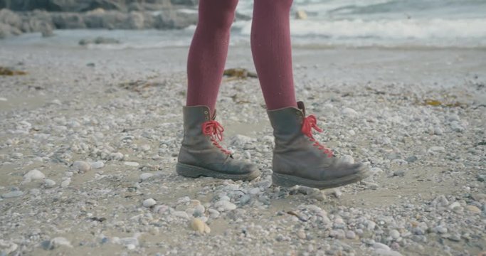 Woman in hikinh boots walking on the beach in winter