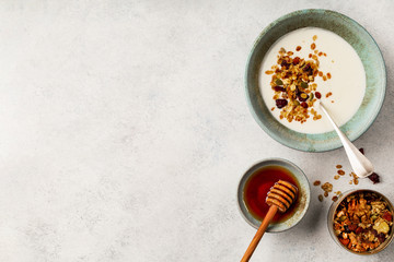 Homemade granola with yogurt and honey on white table, top view, copy space, horizontal 