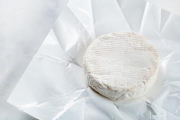 Camembert or brie cheese in white paper
