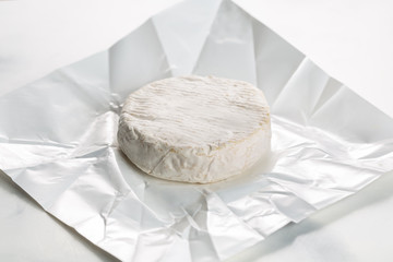 Camembert or brie cheese in white paper