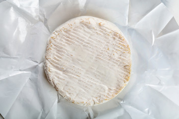 Camembert or brie cheese in white paper