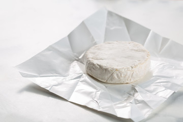 Camembert or brie cheese in white paper