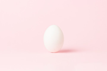 White Chicken Egg on a pink background. Minimalism. Side view