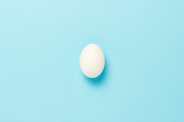 White Chicken Egg on a blue background. Minimalism. Flat lay, top view