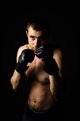 Fototapeta na wymiar A man in gloves for fighting without rules MMA on a black background. Workout concept, combat training