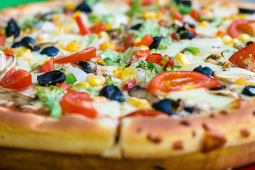 Closeup view on delicious mouthwatering vegan or vegetarian pizza with a lot of vegetables and greenery