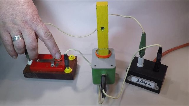 A metal ring hovers on the iron kernel of a coil as alternating current is connected to the coil when a red key is pressed. The metal ring is exposed to magnetic repulsion from the coil. 