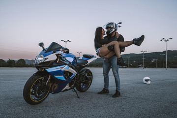Girl and guy bikers love each other. Fooling around and having fun. Love. Motorcycles, helmets, road, leather, sunset.