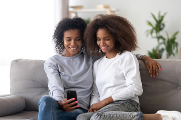 Obraz premium Different ages females sitting on couch at home using smartphone