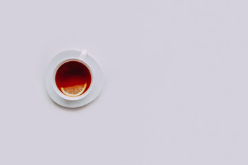 White cup of tea with lemon on a white background