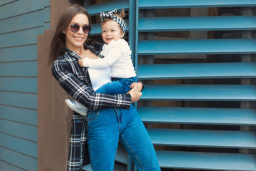 Happy mother and daughter have fun and wearing a jeans clothes in city. Street style family look.