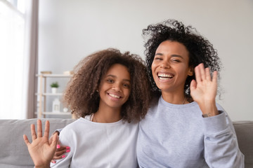 African daughter and mother looking at camera make video call