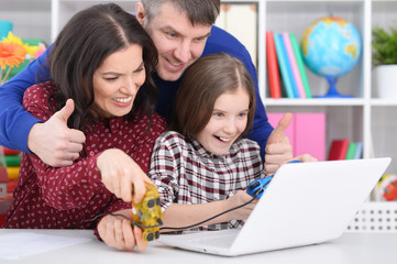 Portrait of parents and daughter playing computer game with laptop