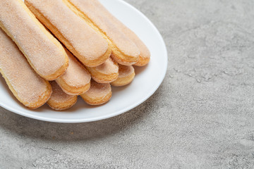 Italian Savoiardi ladyfingers Biscuits in plate on concrete backgound