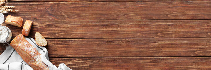 Fresh tasty bread and jar with white wheat flour on wooden background