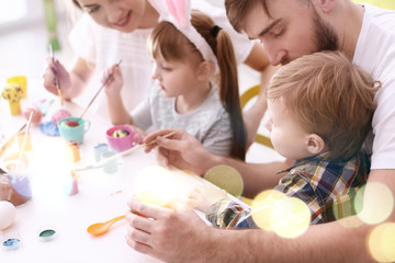 Family painting Easter eggs together at table