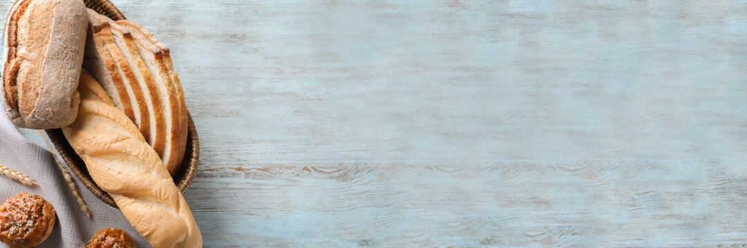 Breadbasket with different bakery products on wooden background