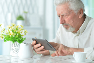 Portrait of thoughtful senior man using tablet