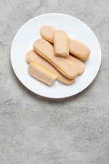 Italian Savoiardi ladyfingers Biscuits in plate on concrete backgound