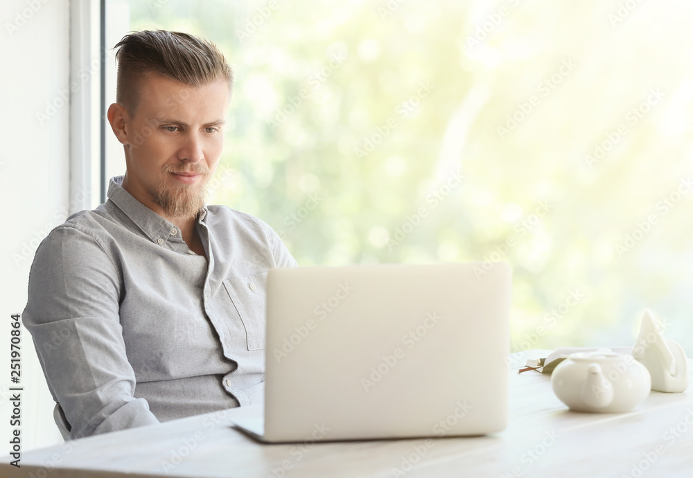 Wall mural handsome freelancer with laptop in cafe