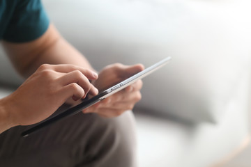 Young freelancer working on tablet computer at home, closeup