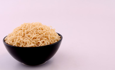 Noodles in a black bowl with a white backdrop.