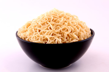 Noodles in a black bowl with a white backdrop.