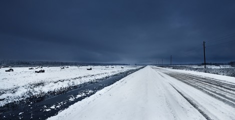 Unpaved gravel road near a water canal under snow