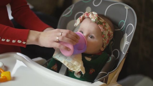 the little girl is drinking from the trough