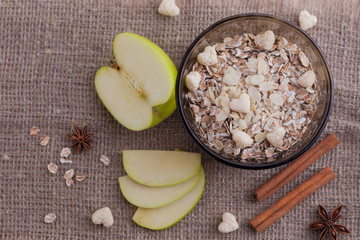 Healthy food. Muesli in a bowl on a light background with a green apple. Breakfast porridge on linen background