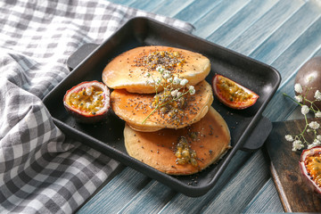 Frying pan with tasty pancakes and passion fruit on table