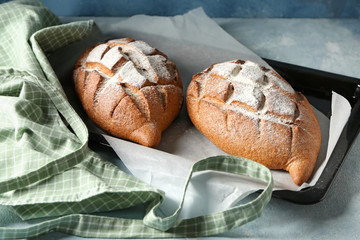 Baking sheet with tasty fresh bread on table