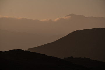 A silhouette of Bowfell created by evening light, seen from Loughrigg Fell, Lake District, UK
