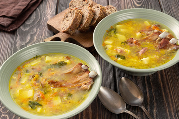 Two plates of delicious yellow split peas soup with smoked pork ribs  on a wooden table.