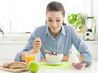 Smiling woman having breakfast at home