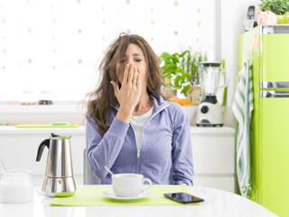 Tired woman having breakfast at home