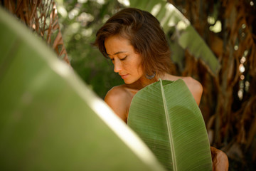 beautiful woman with freckles and brunette hair posing with green banana palm leaf in tropical Jungle in Bali © Антон Паршунас