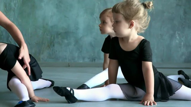 Girl dancer in ballet school learns to dance. Little Ballerina in training in black dancing suit. Children's ballet school.