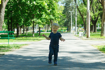 Funny toddler running and jumping in the spring or autumn alley.