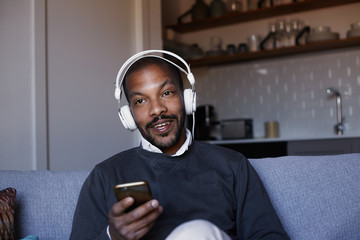 Attractive African American man with white headphones listening to music on his phone. Concept of relaxation