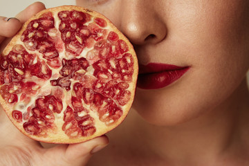 Beauty woman with orange pomegranate cut in half over white background. Attractive fresh vitamin...