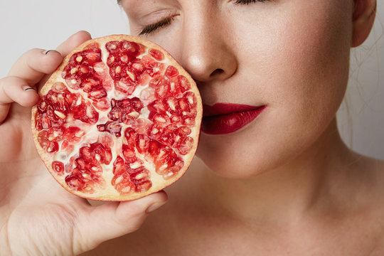 Beauty woman with orange pomegranate cut in half over white background. Attractive fresh vitamin concept. Closeup.